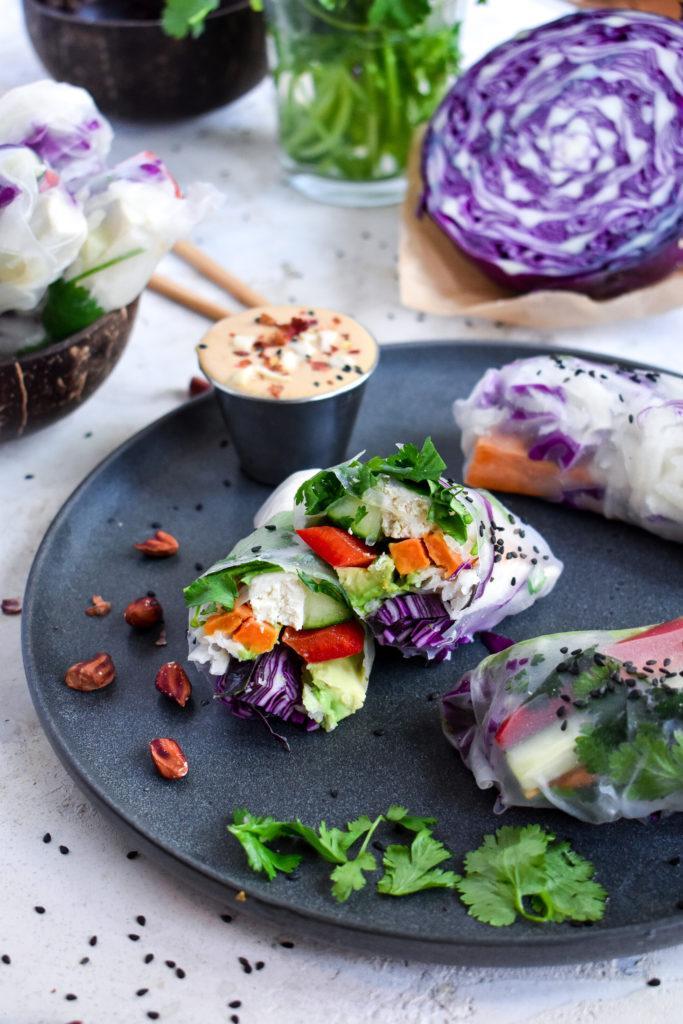 potato spring roll recipe with rainbow vegetables on a plate with peanuts, cilantro, and peanut dipping sauce