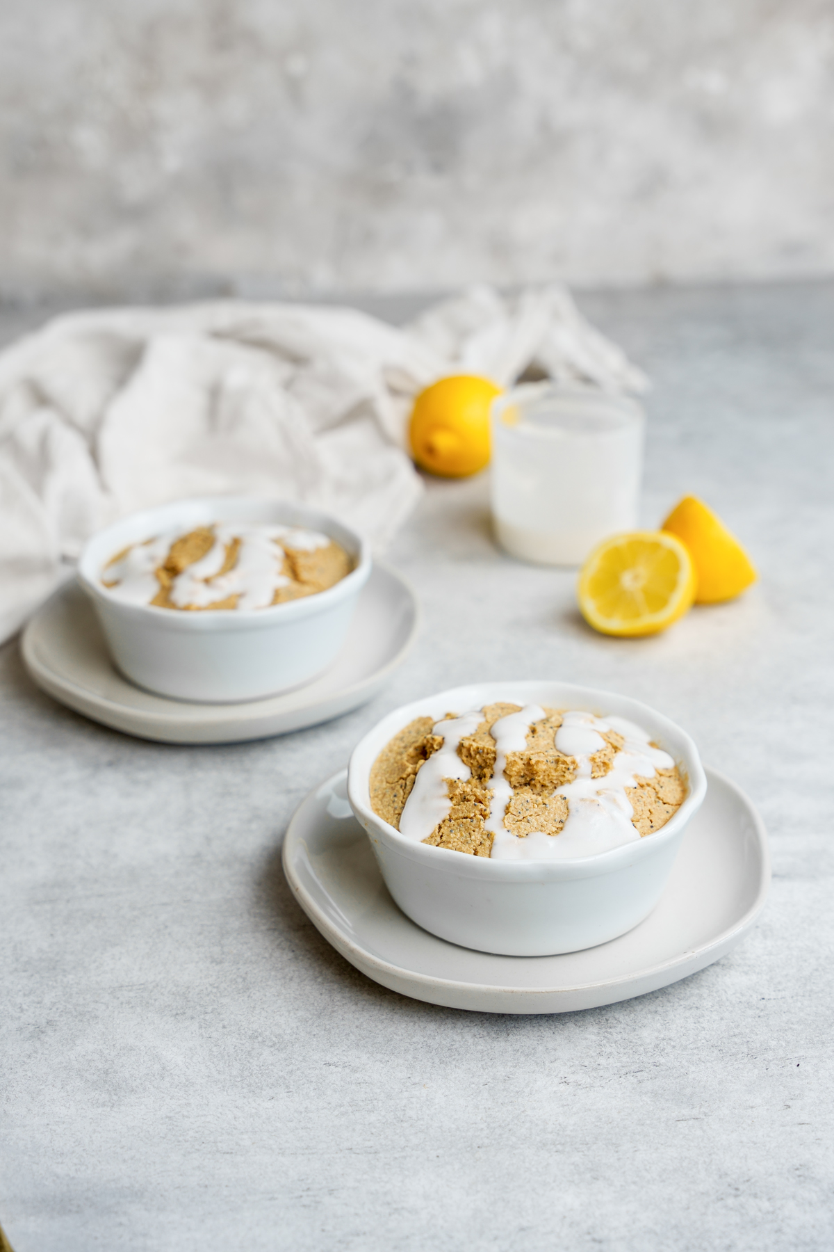 two bowls of the lemon poppy seed baked oatmeal with lemons and the glaze