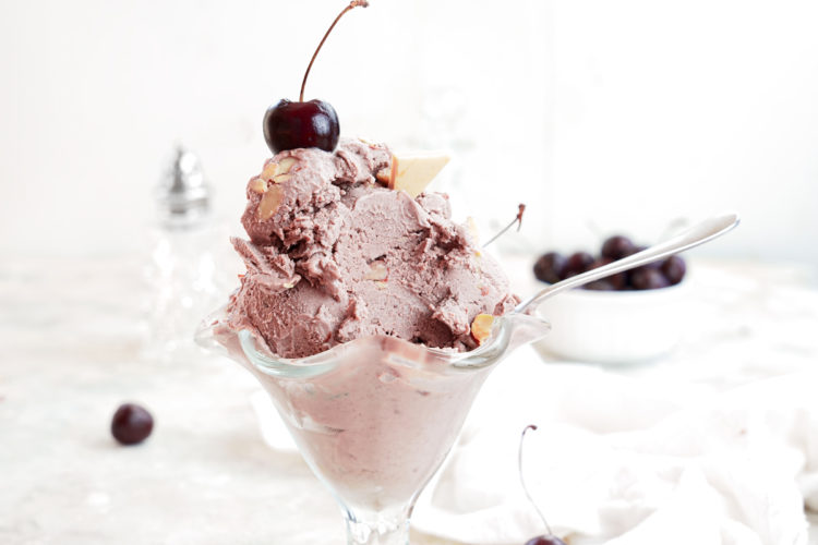 cherry almond ice cream in glass ice cream cup with fresh cherries