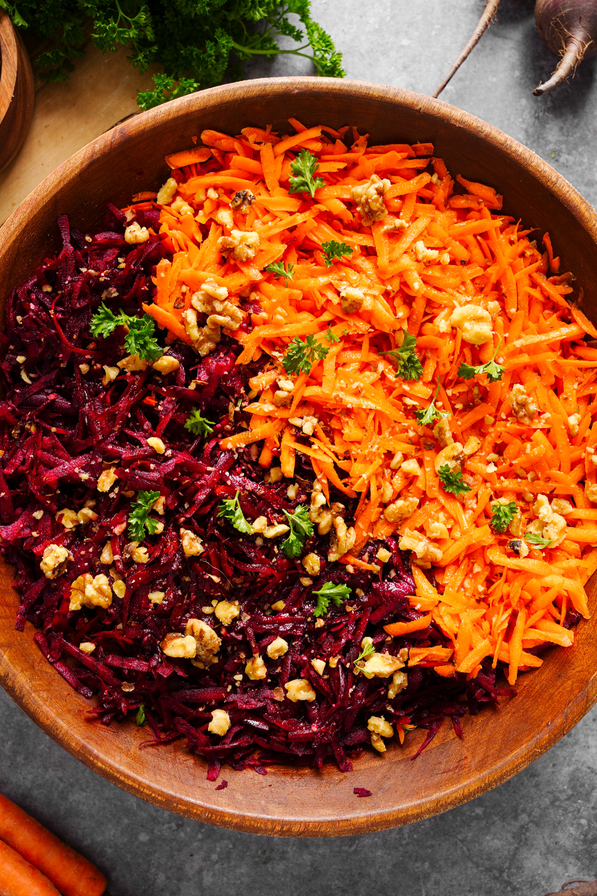 a close up of the beet carrot salad topped with walnuts and fresh parsley