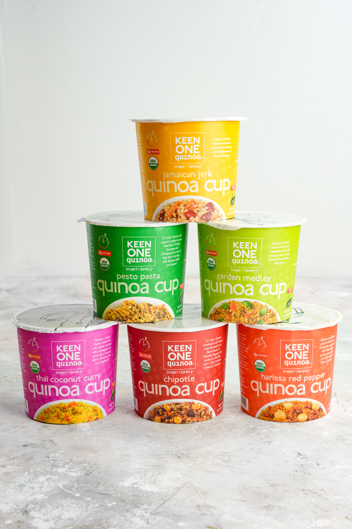 keen one cups stacked on top showing the individual flavors: jamaican jerk, pesto pasta, garden medley, thai coconut curry, chipotle, harissa red pepper.