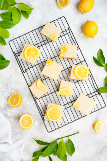 creamy vegan lemon squares with decorative lemons and fresh cut lemon leaves