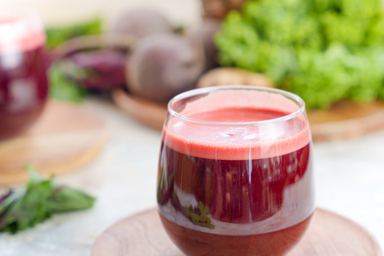 kale beet juice in a cup with pineapple and kale in the background
