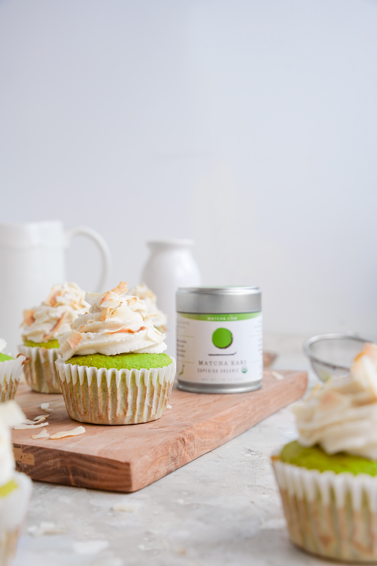 the matcha coconut cupcakes with the matcha.com tin on a platter