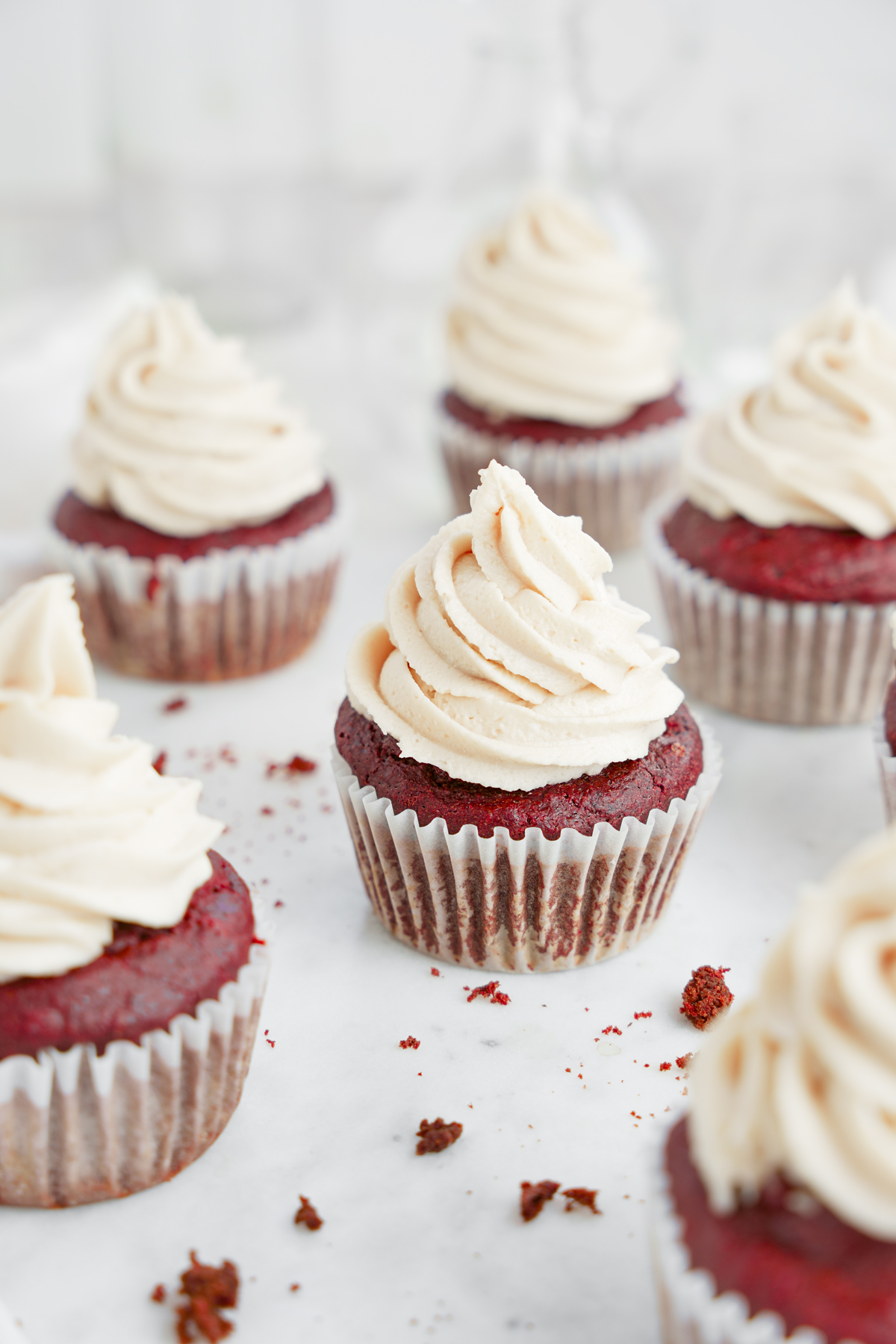 healthy vegan red velvet cupcakes lined up topped with vegan cream cheese frosting