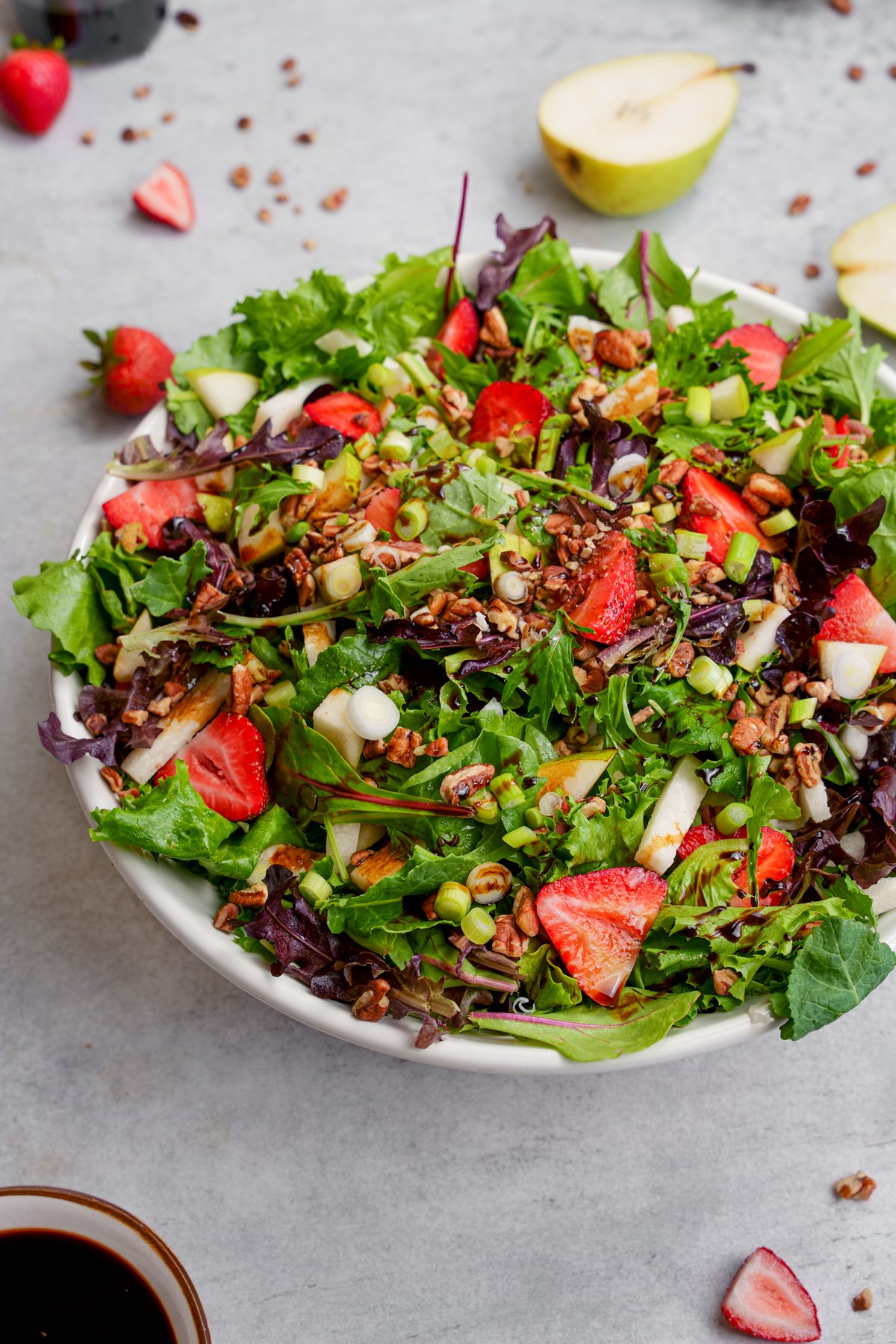 jicama salad recipe with fresh strawberries, pears, and nuts over a bed of spring mix