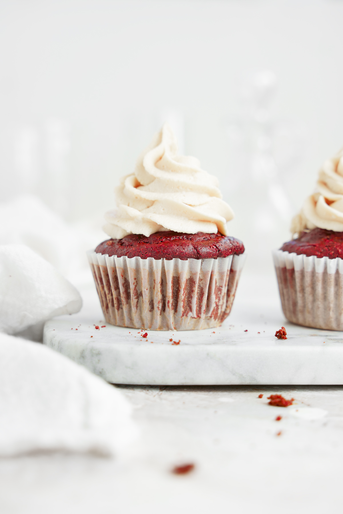 two of the vegan red velvet cupcakes topped with the non-dairy cream cheese frosting
