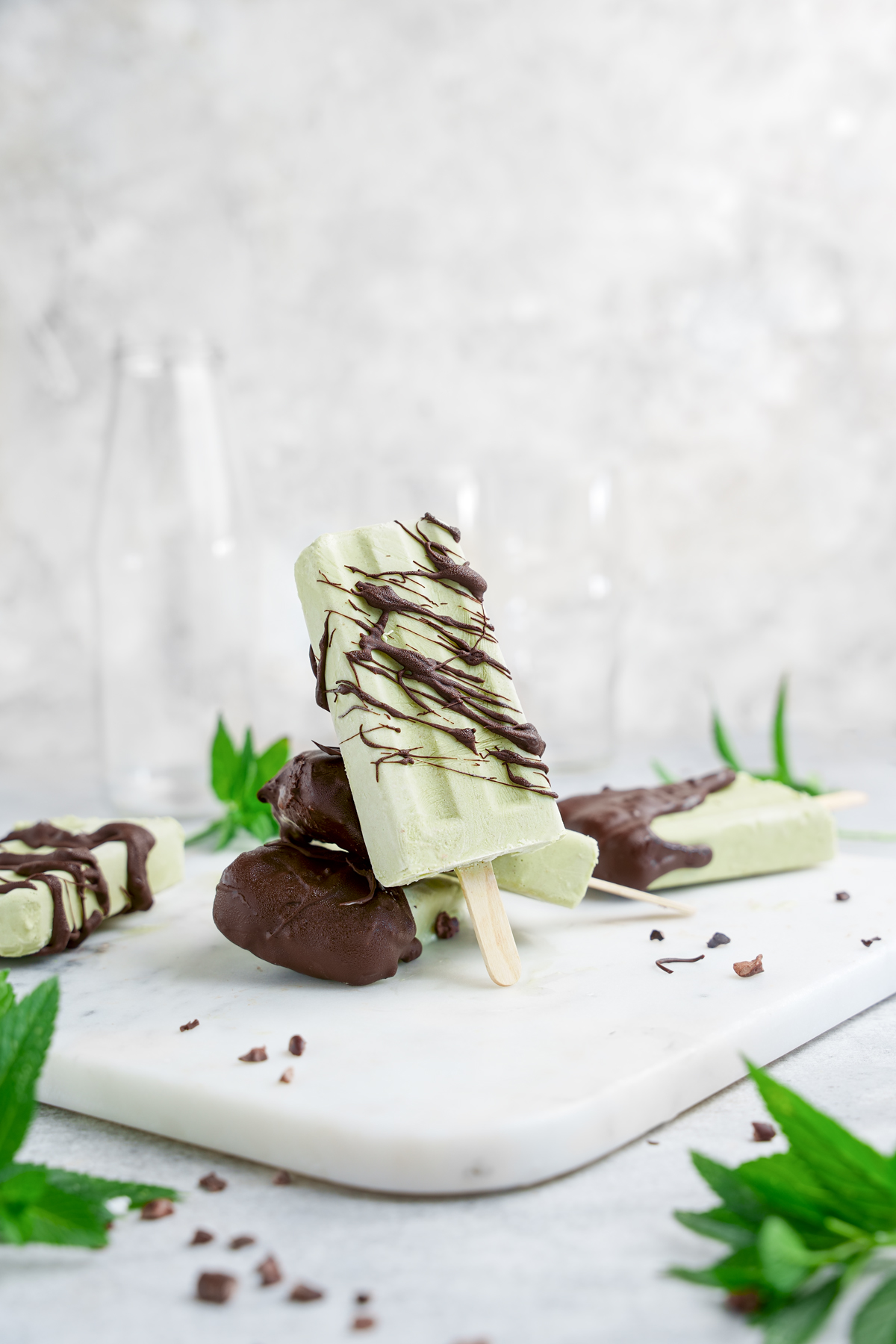 the mint chocolate chip popsicles stacked on top of each other and drizzled with dark chocolate