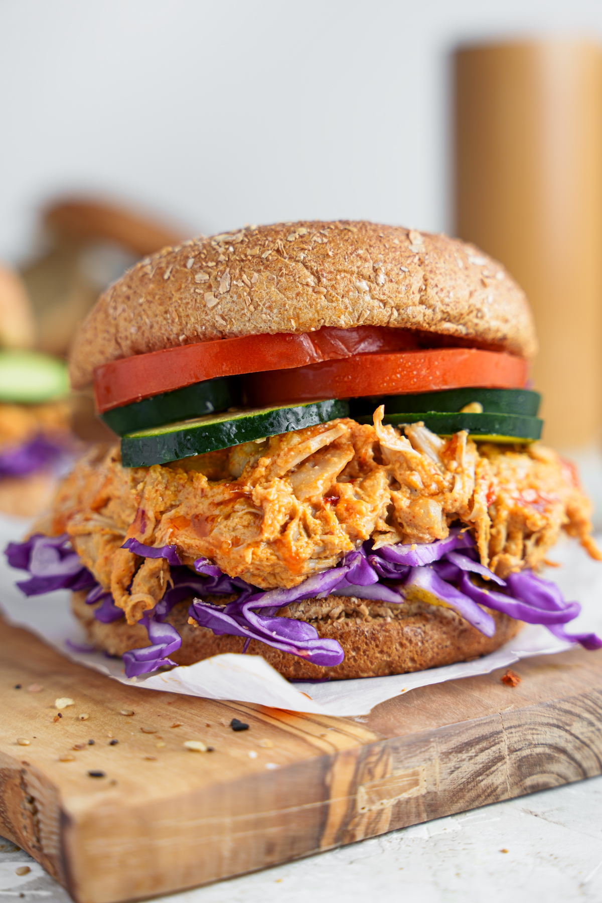 close up of the buffalo pulled jackfruit burger with cucumbers, tomatoes, and purple cabbage