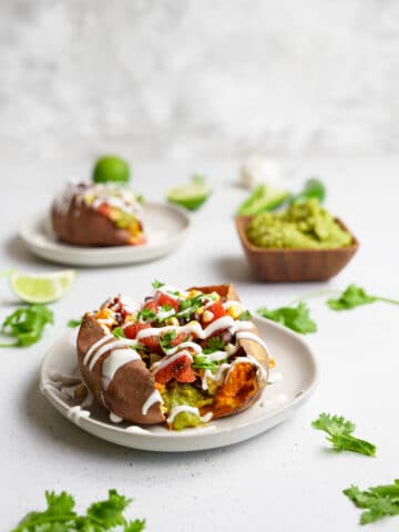 plates with the vegan taco stuffed sweet potatoes and a bowl of guacamole
