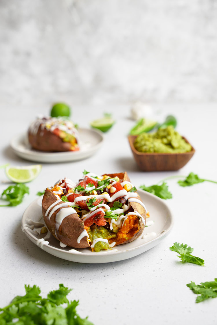 plates with the vegan taco stuffed sweet potatoes and a bowl of guacamole
