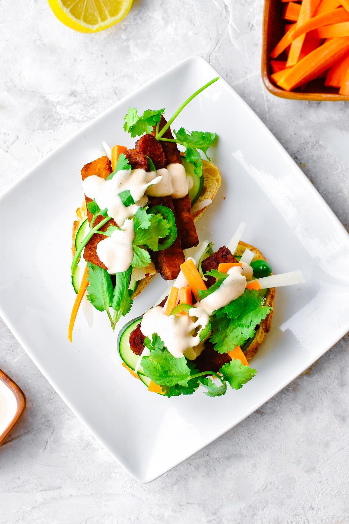 tempeh banh mi split in half with the carrots, cilantro, daikon radish, cucumbers, jalapeños, and temoeh