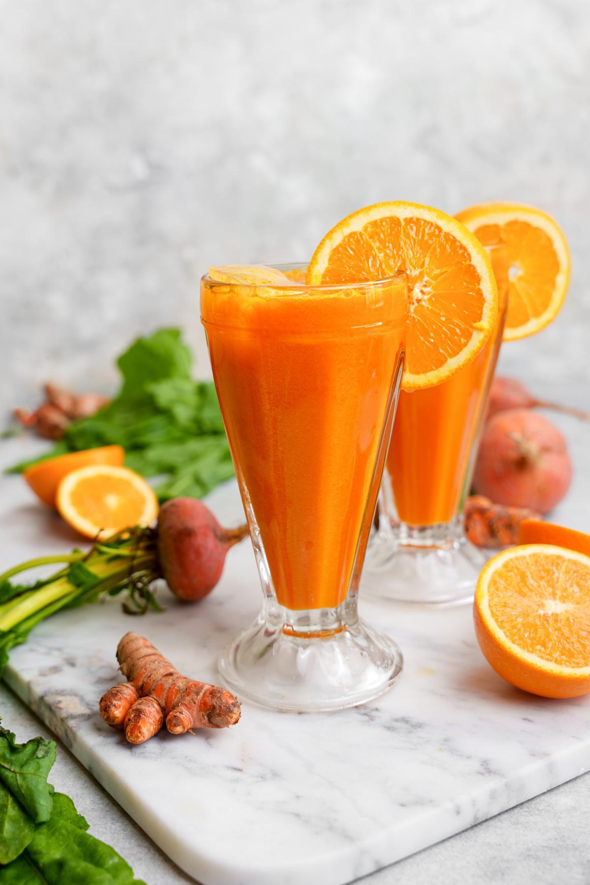 the yellow beet juice in a glass cut with fresh oranges and turmeric