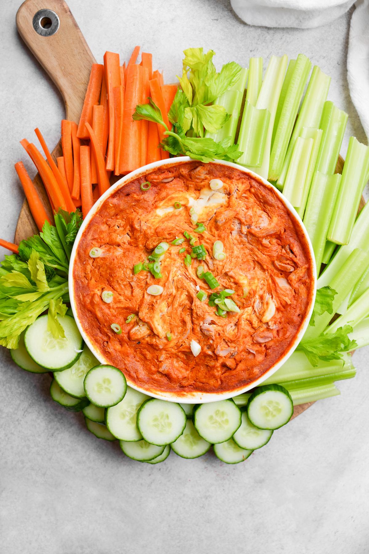 healthy jackfruit buffalo dip baked and with fresh celery, cucumbers, and carrots