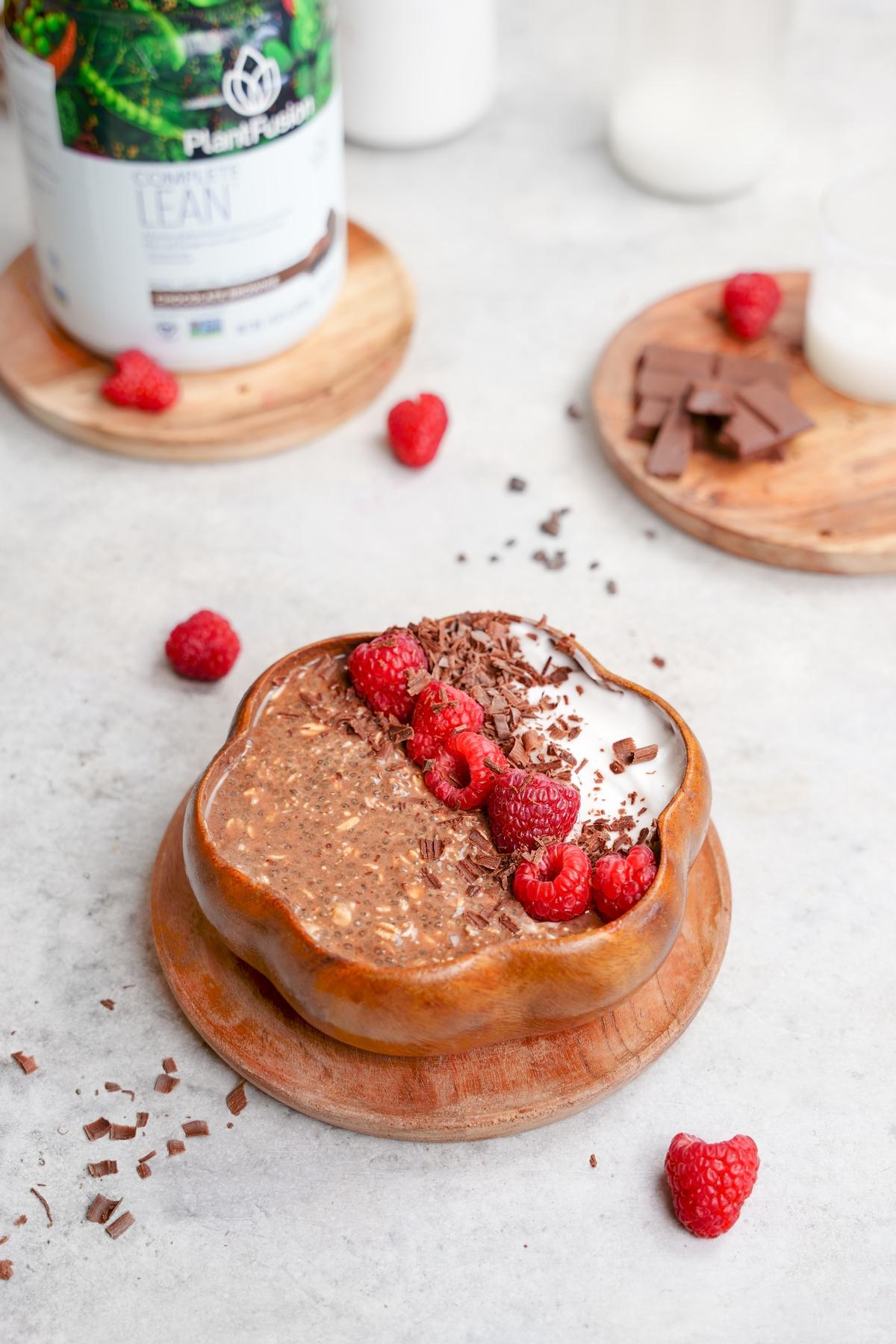 raspberry chocolate overnight oats in a wooden bowl with the plantfusion protein powder