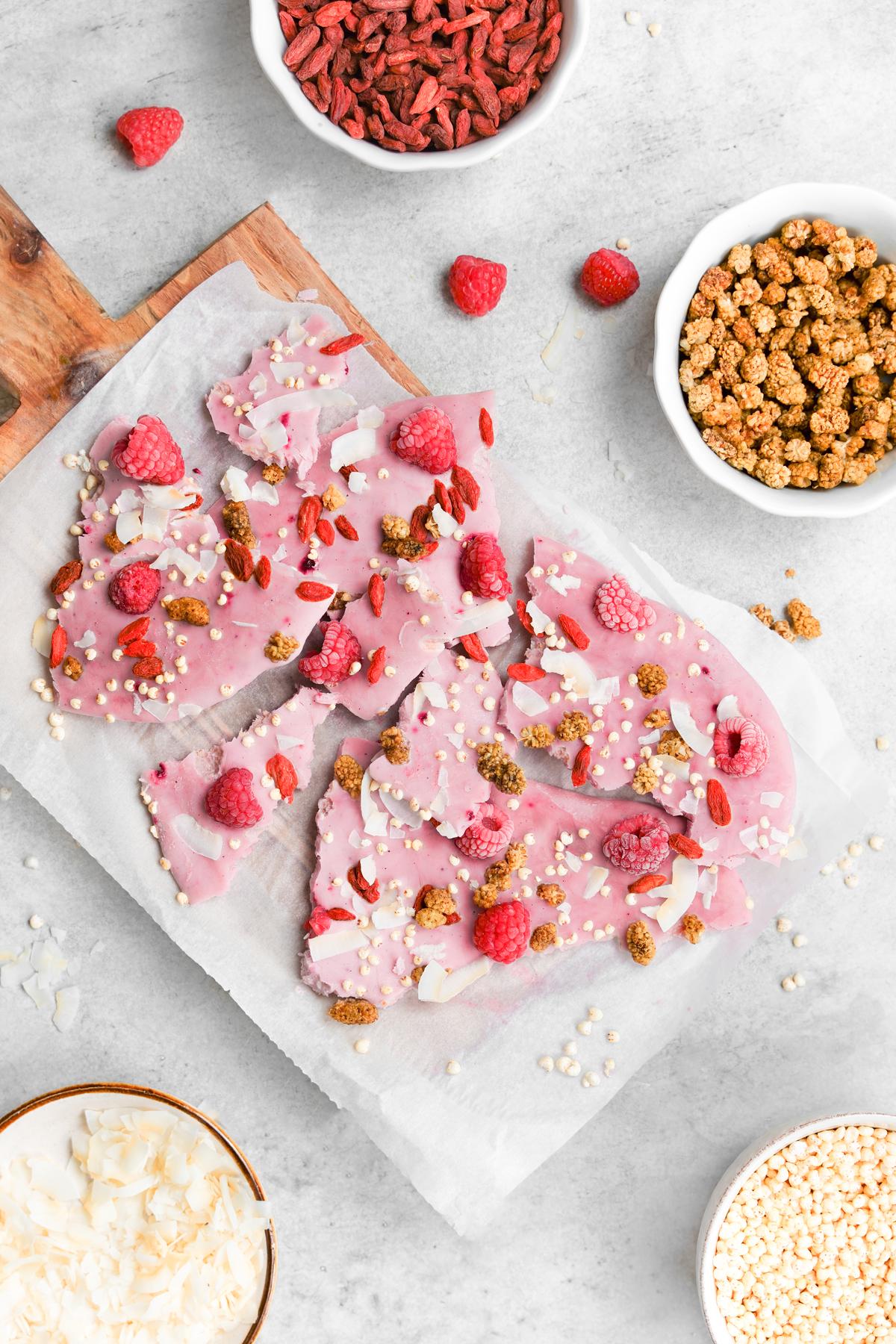 looking down at the pieces of the yogurt bark with bowls of the toppings