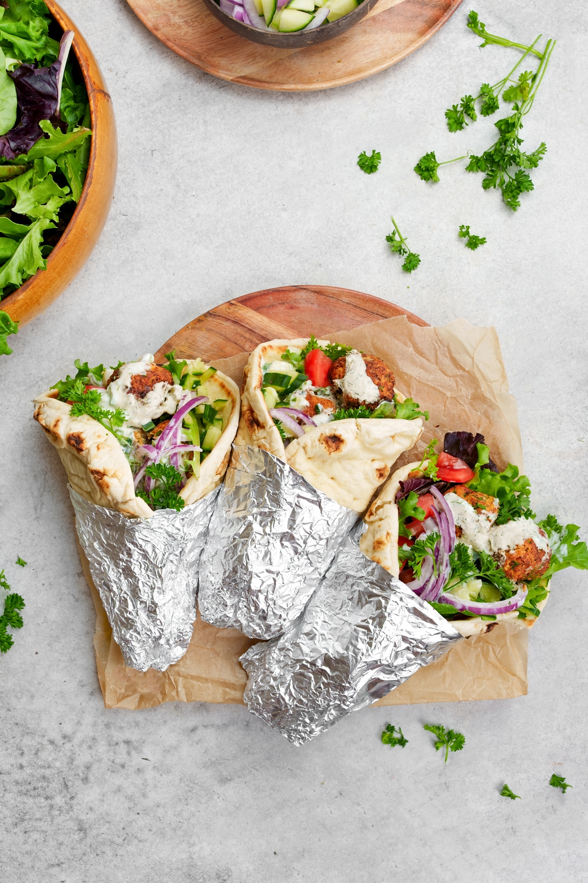 looking down at the wrapped up falafel gyros with fresh parsley and greens around them