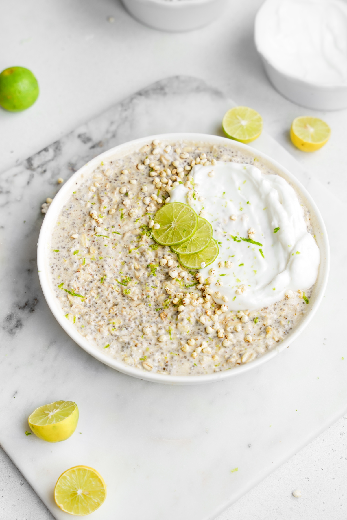 the key lime pie overnight oats in a large bowl topped with vegan yogurt, puffed millet, lime zest and fresh key limes