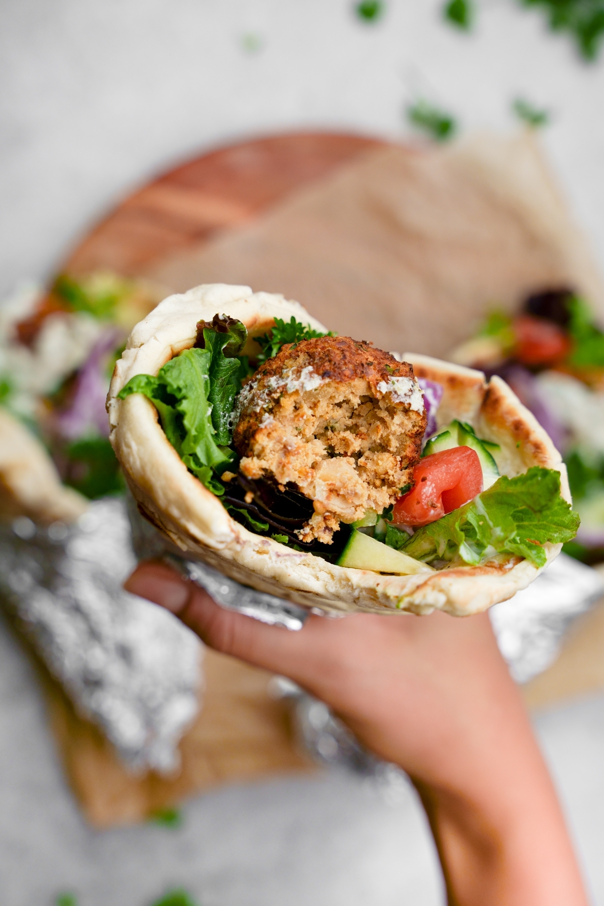 someone holding the falafel gyro with a bite taken out to show the fluffy texture