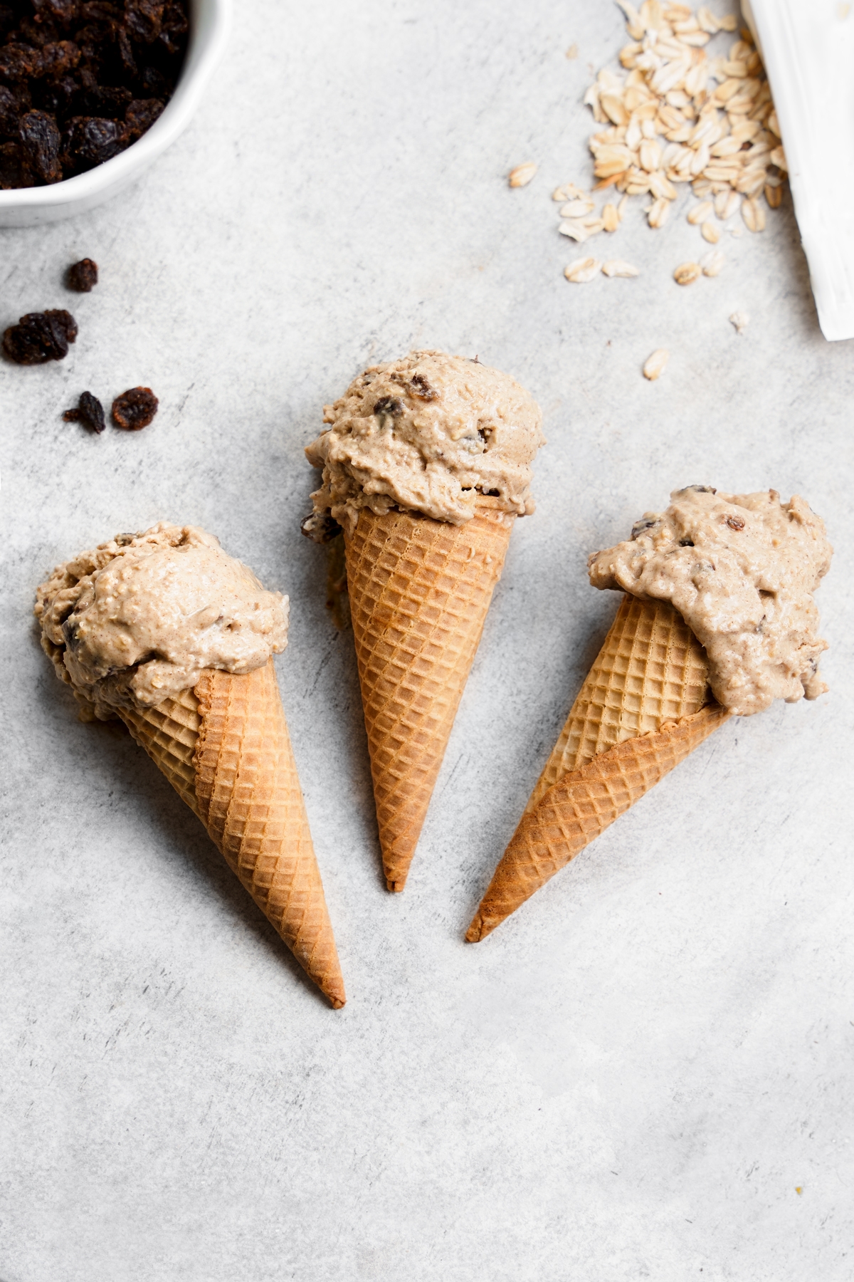 the oatmeal raisin ice cream scooped into cones laying flat on the surface