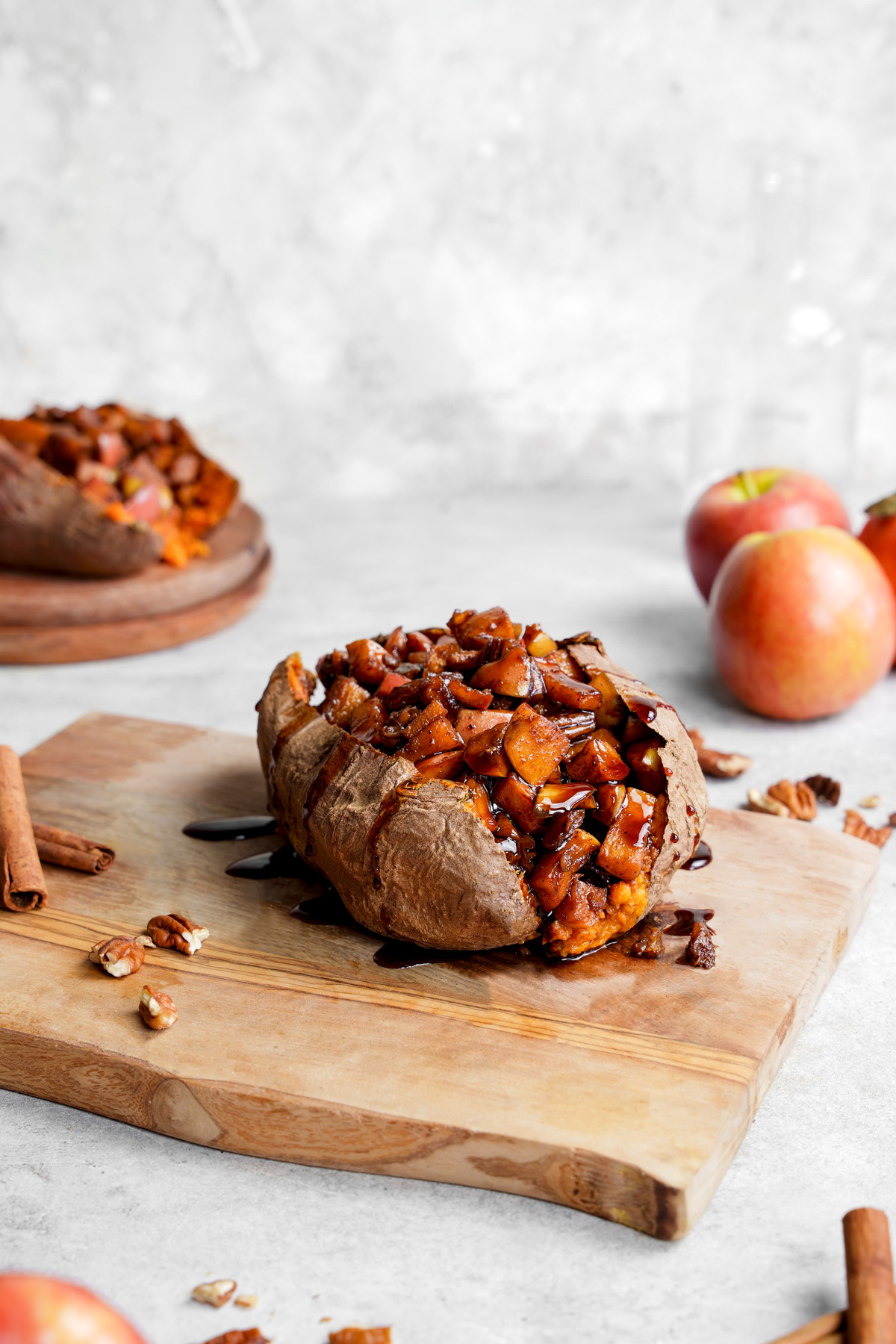 the apple stuffed sweet potatoes resting on a bored with date syrup drizzling out of them