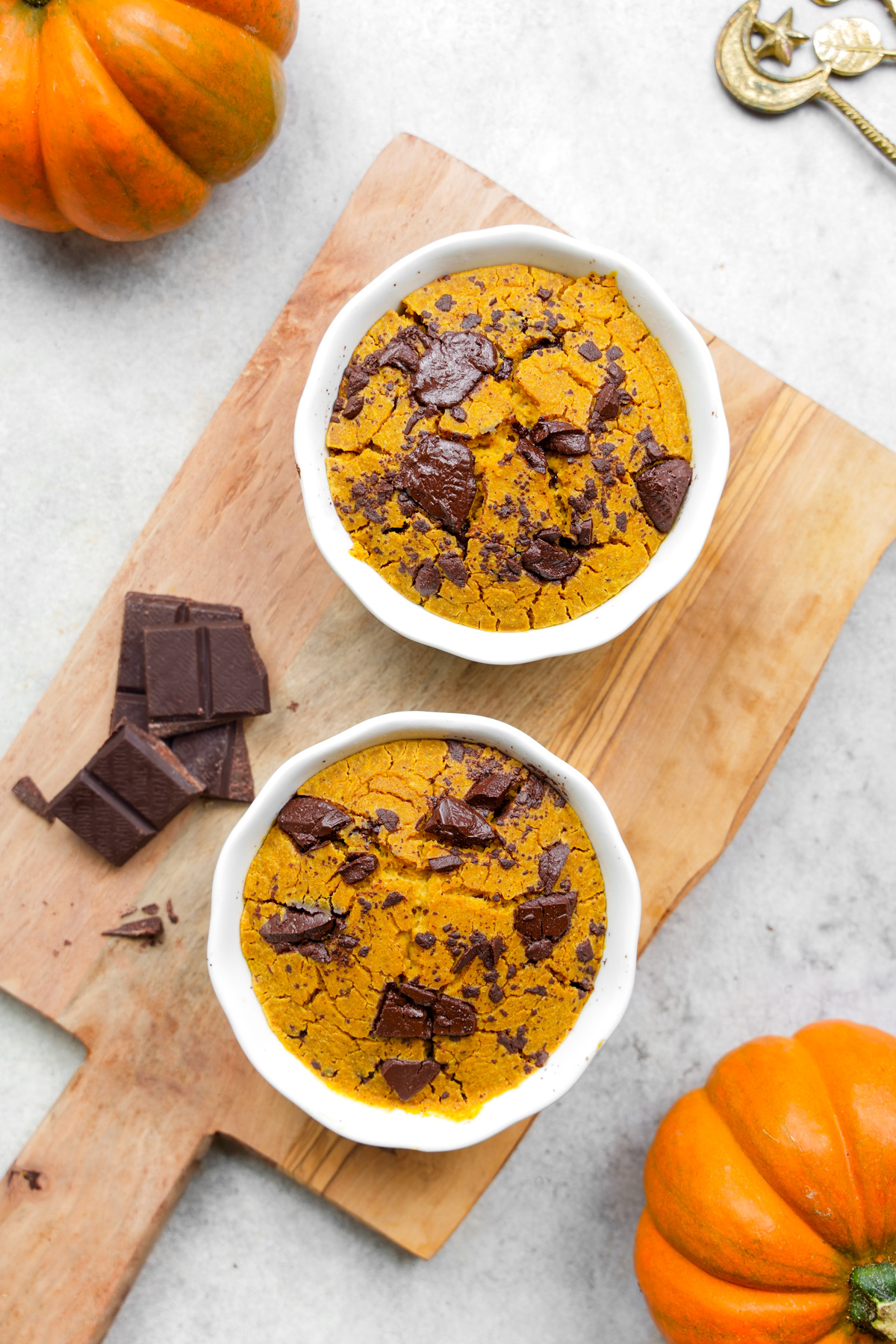 looking down at the two bowls of pumpkin baked oats with pumpkins and chocolate around them