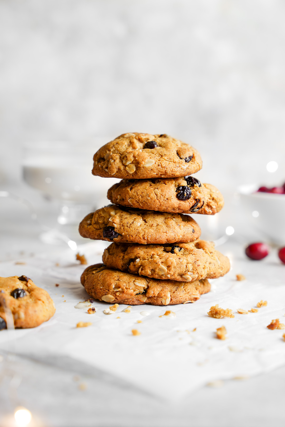 the cookies stacked on top of each other with crumbs and fresh cranberries around them