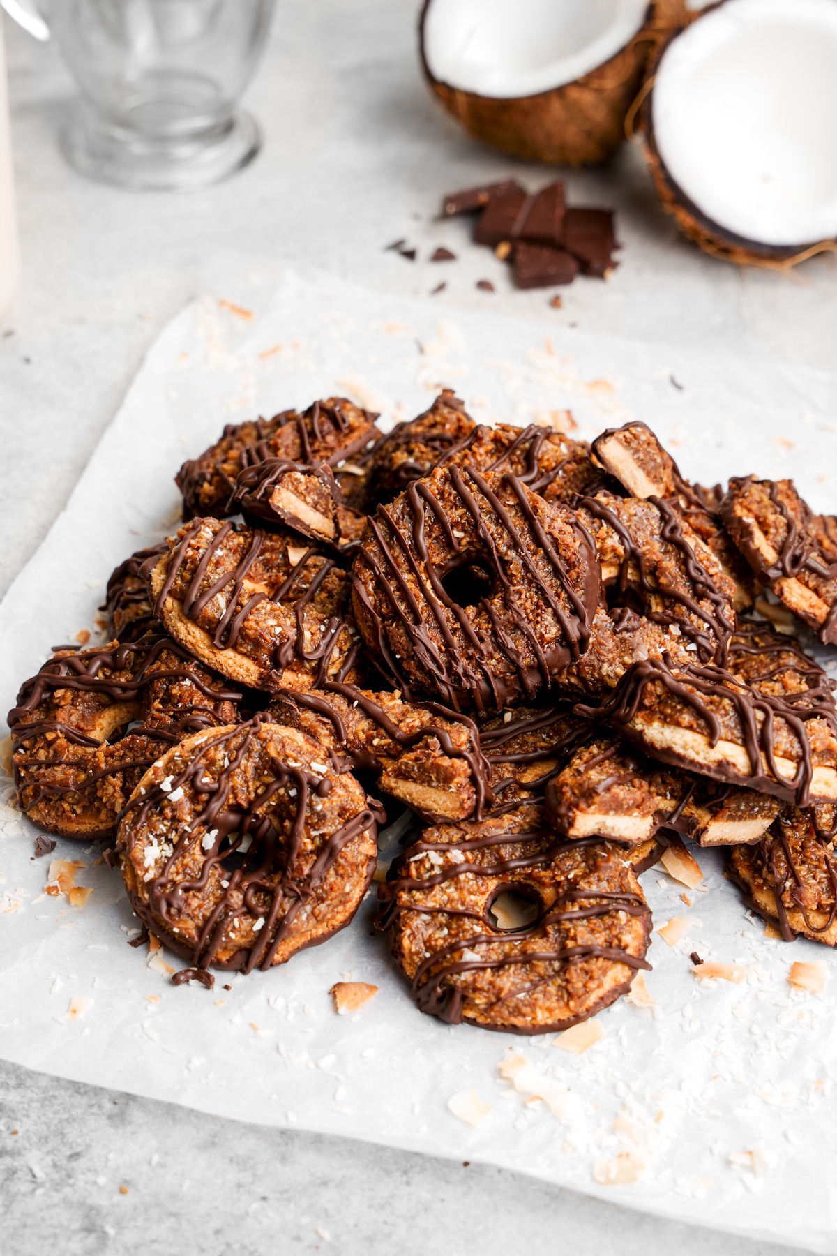 the vegan samoas piled on top of each other with coconut and chocolate in the background