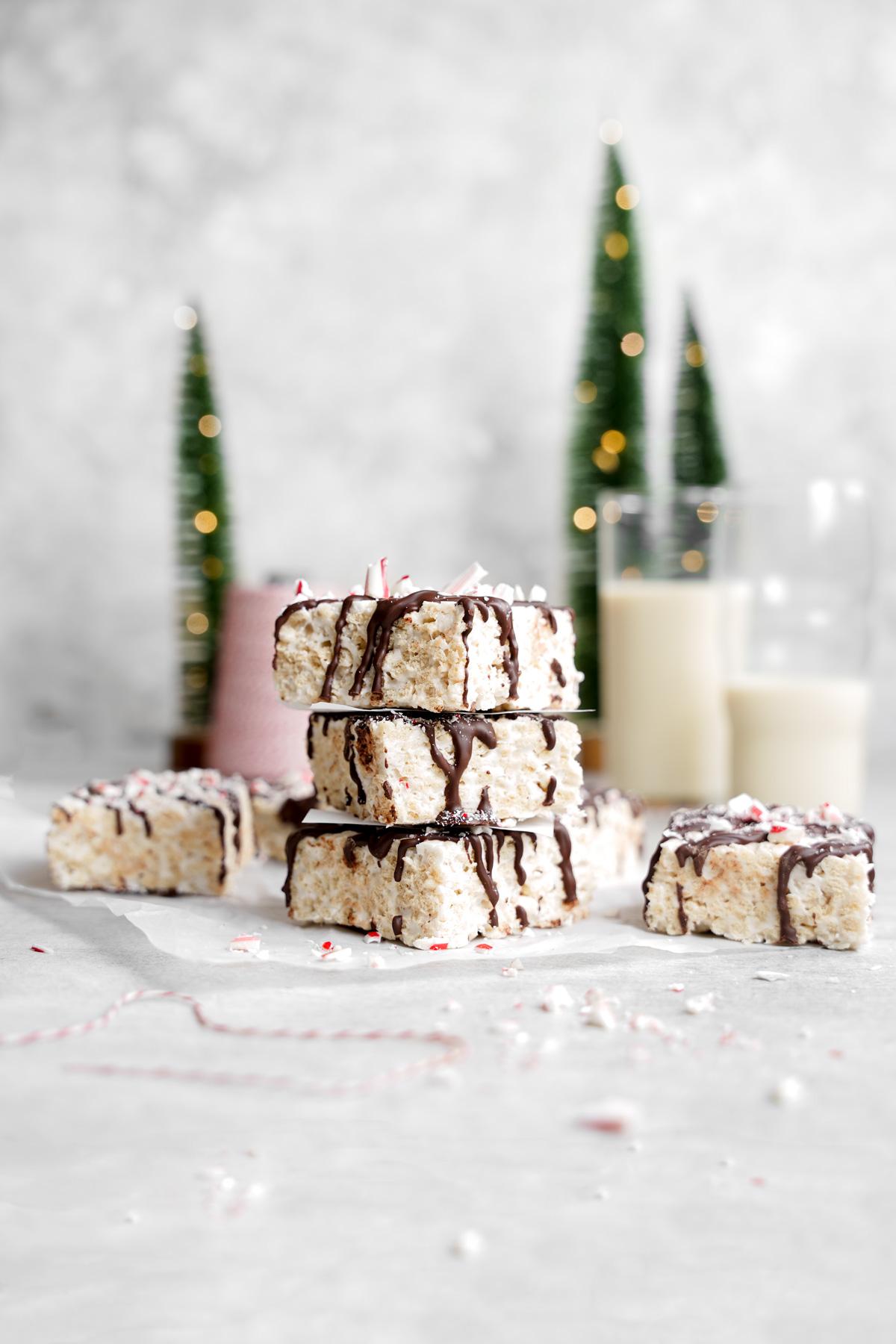 the vegan peppermint bark rice krispie treats stacked on top of each other with christmas trees in the back