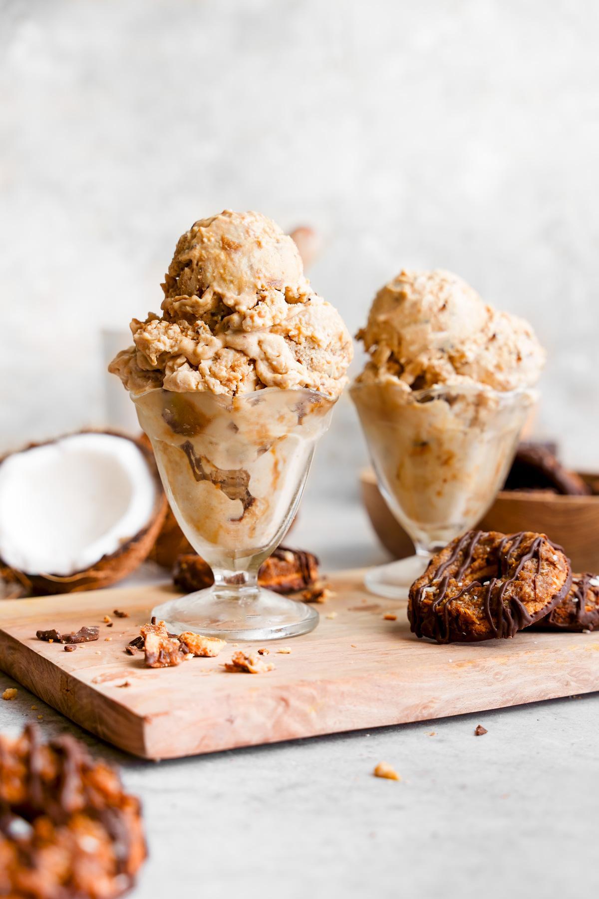 the samoa ice cream in ice cream cups with samoa cookies and coconut all around