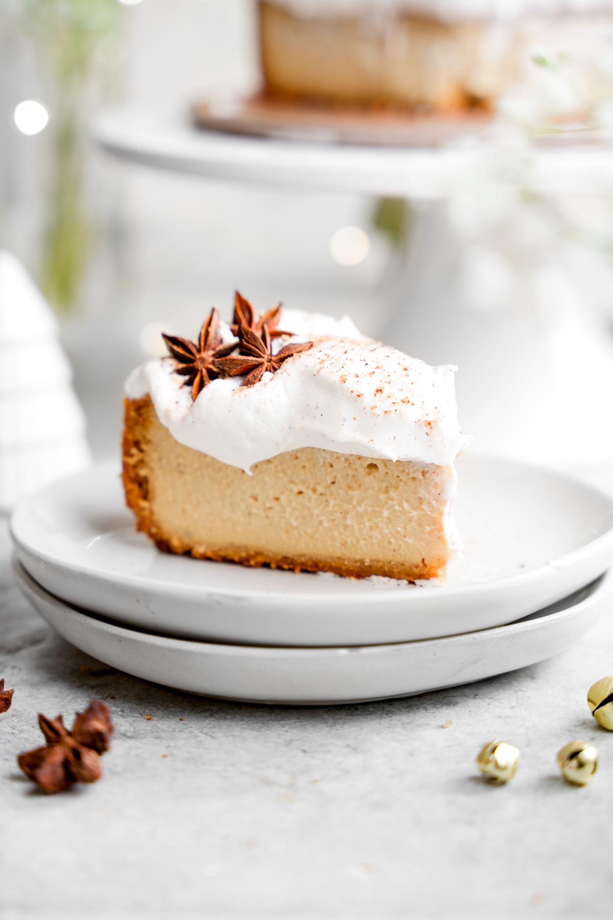 a slice of the vegan eggnog cheesecake with the whipped topping an nutmeg on top