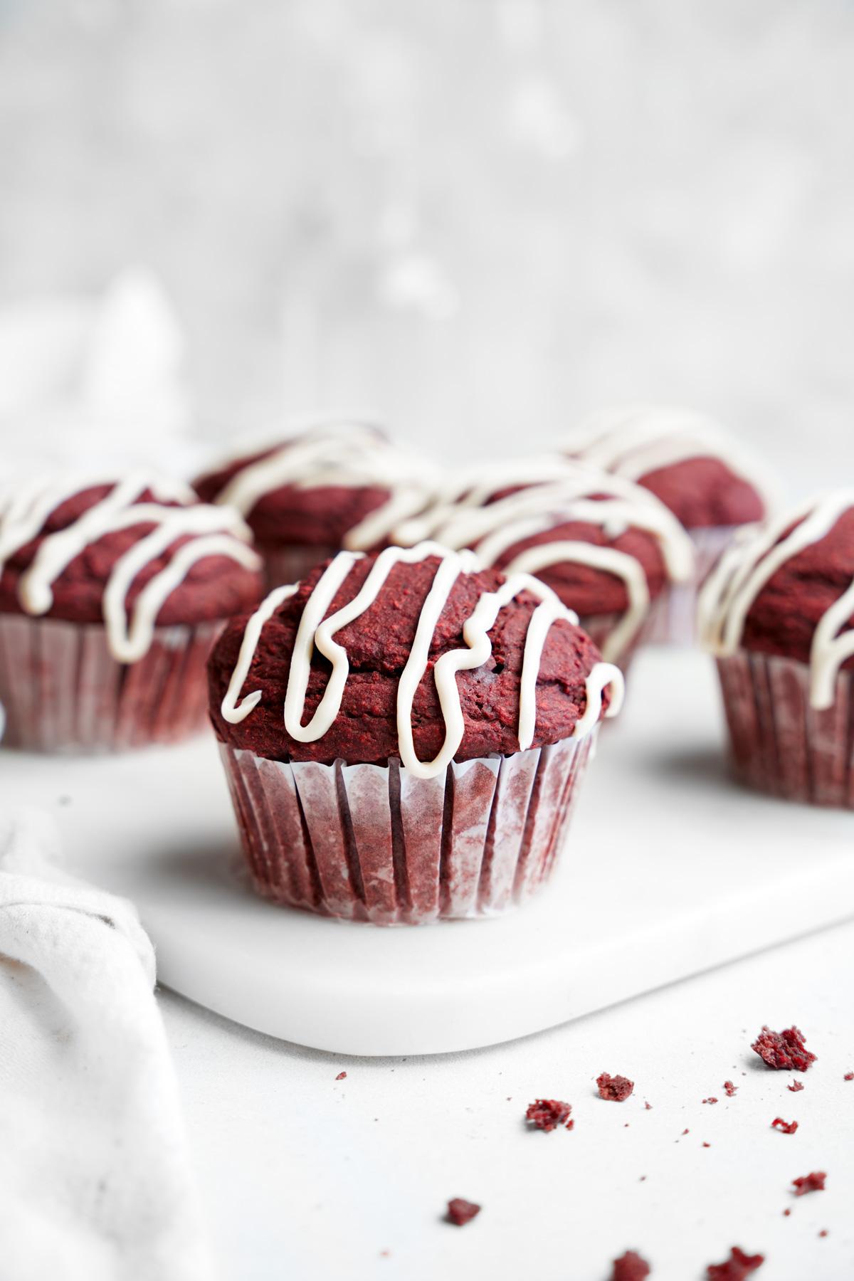 the vegan red velvet muffins lined up with the cream cheese glaze on top
