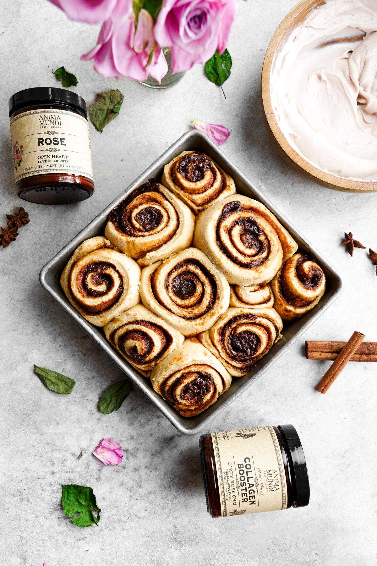 the chai cinnamon rolls in a baking dish without any frosting on top and with the anima mundi products
