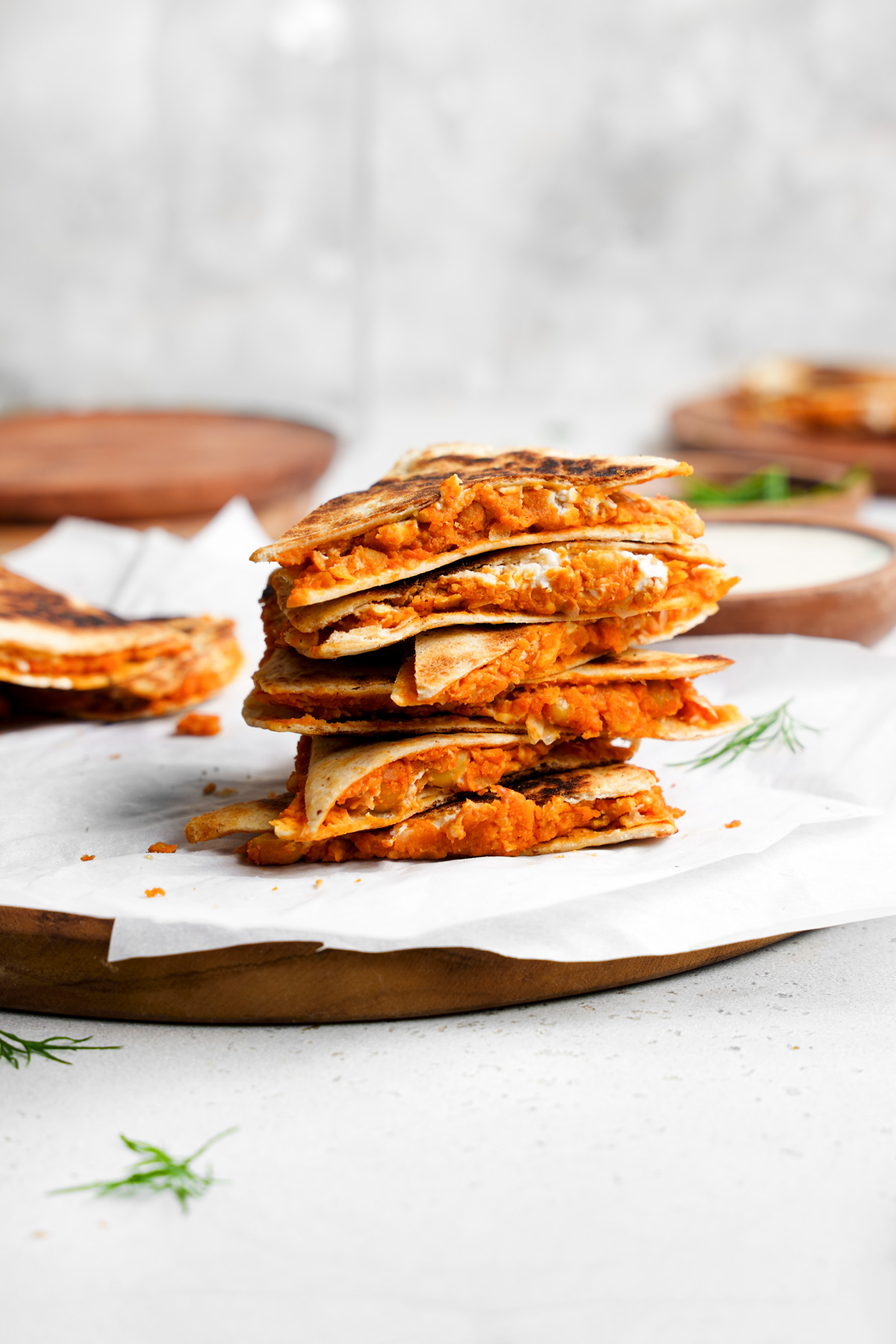 the buffalo chickpea quesadillas stacked on top of each other with the vegan ranch in the background