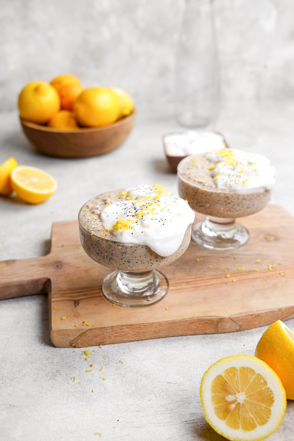 the lemon poppyseed overnight oats in containers with fresh lemon zest and vegan yogurt on top