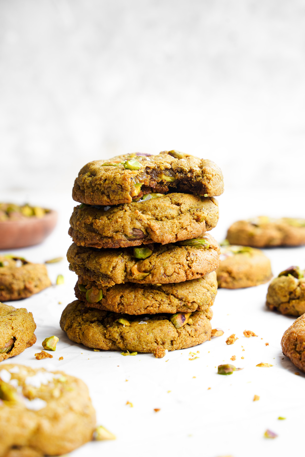a close up of the vegan pistachio cookies with a bite taken out of the top one to show the soft and chewy texture
