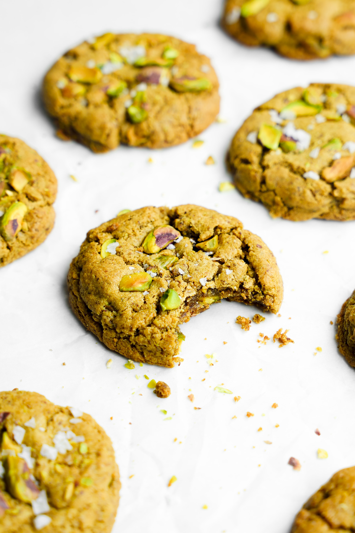 a close up of the vegan pistachio cookies with a bite taken out of it to show the creamy texture