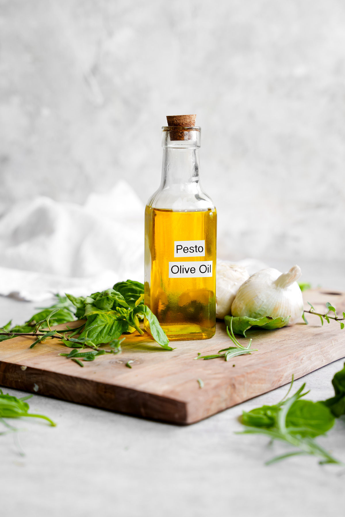 the pesto olive oil in a glass jar with fresh herbs around it