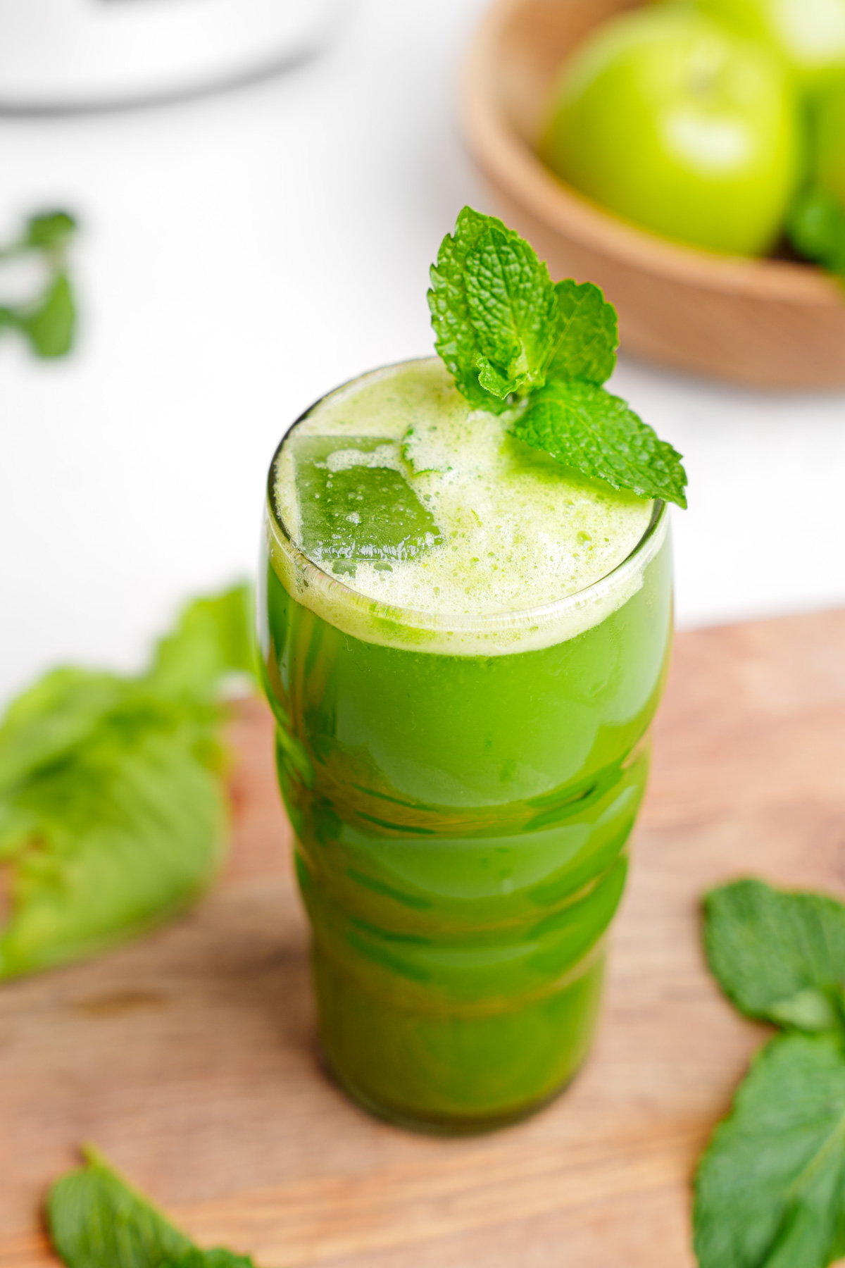 close up of the collard green juice in a tall glass with a fresh mint garnish