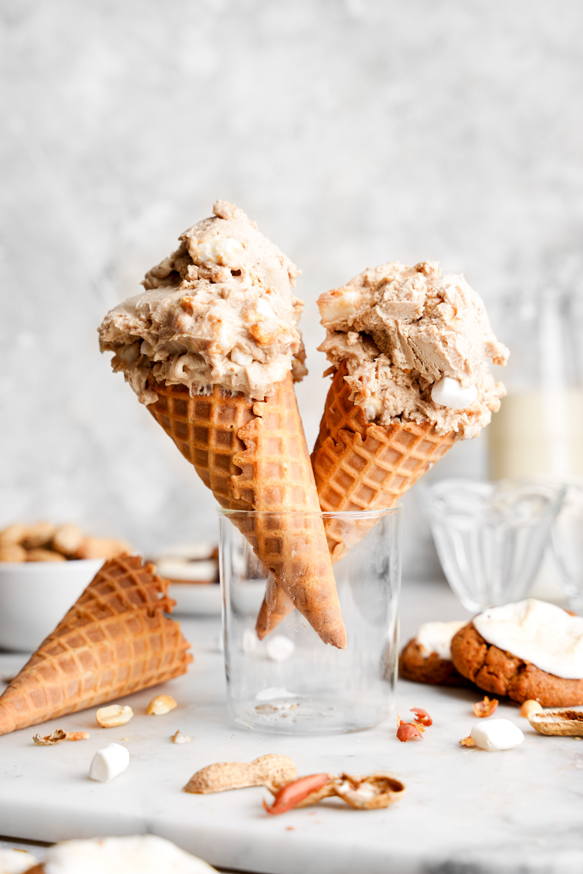 the fluffernutter ice cream in cones with fresh peanuts and mini marshmallows around it