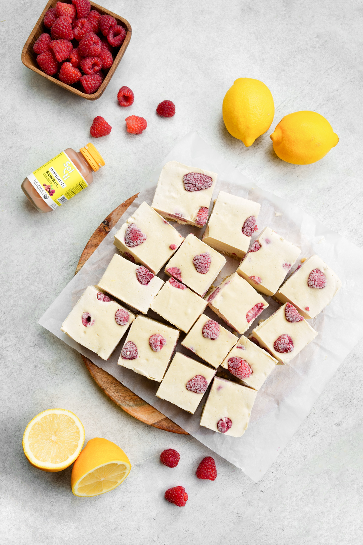 the raspberry lemon bars on a plate cut up with the sol-ti immuni-ti bottle next to them