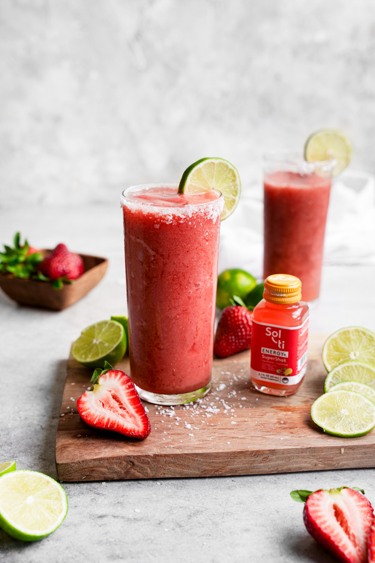 the strawberry margarita mocktail  with the energy supershot and fresh strawberries and lime all around it