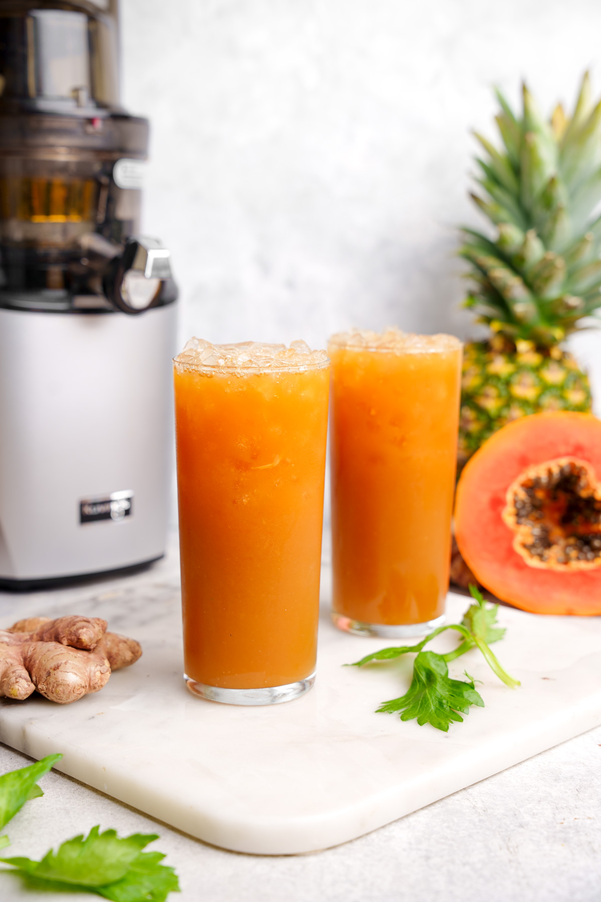 the papaya juice with the fresh ingredients all around it and the kuvings juicer in the background