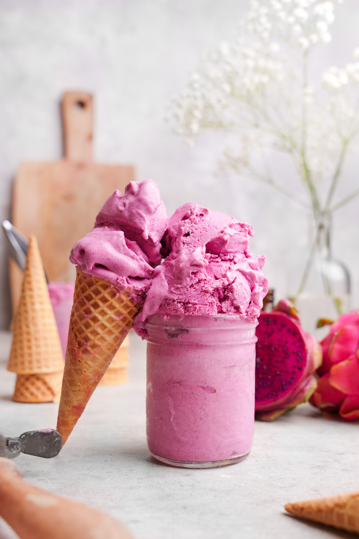 the dragon fruit ice cream in a container with a cone of melting ice cream leaning against it