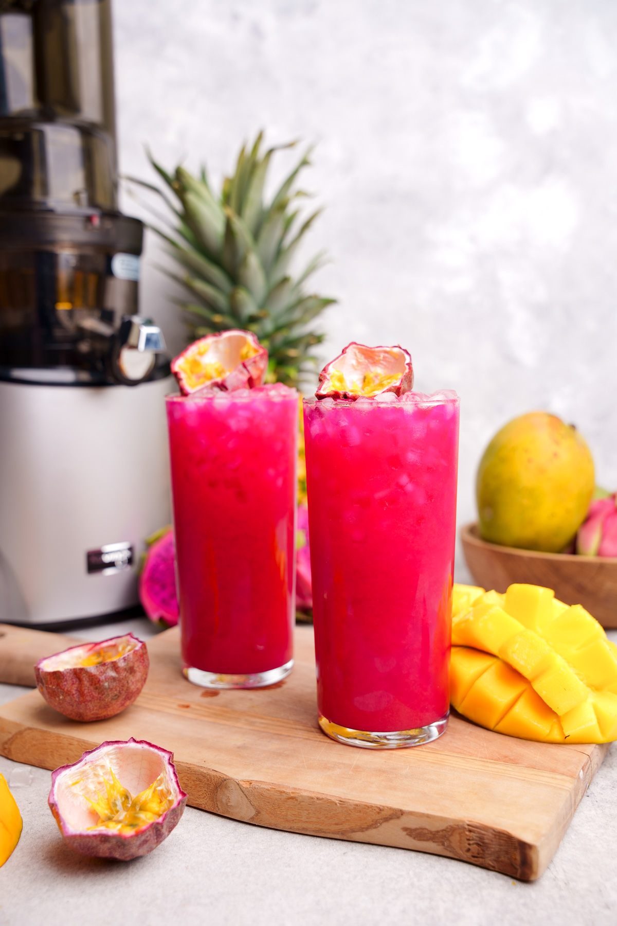 the tall glasses of tropical fruit juice garnished with a fresh passion fruit