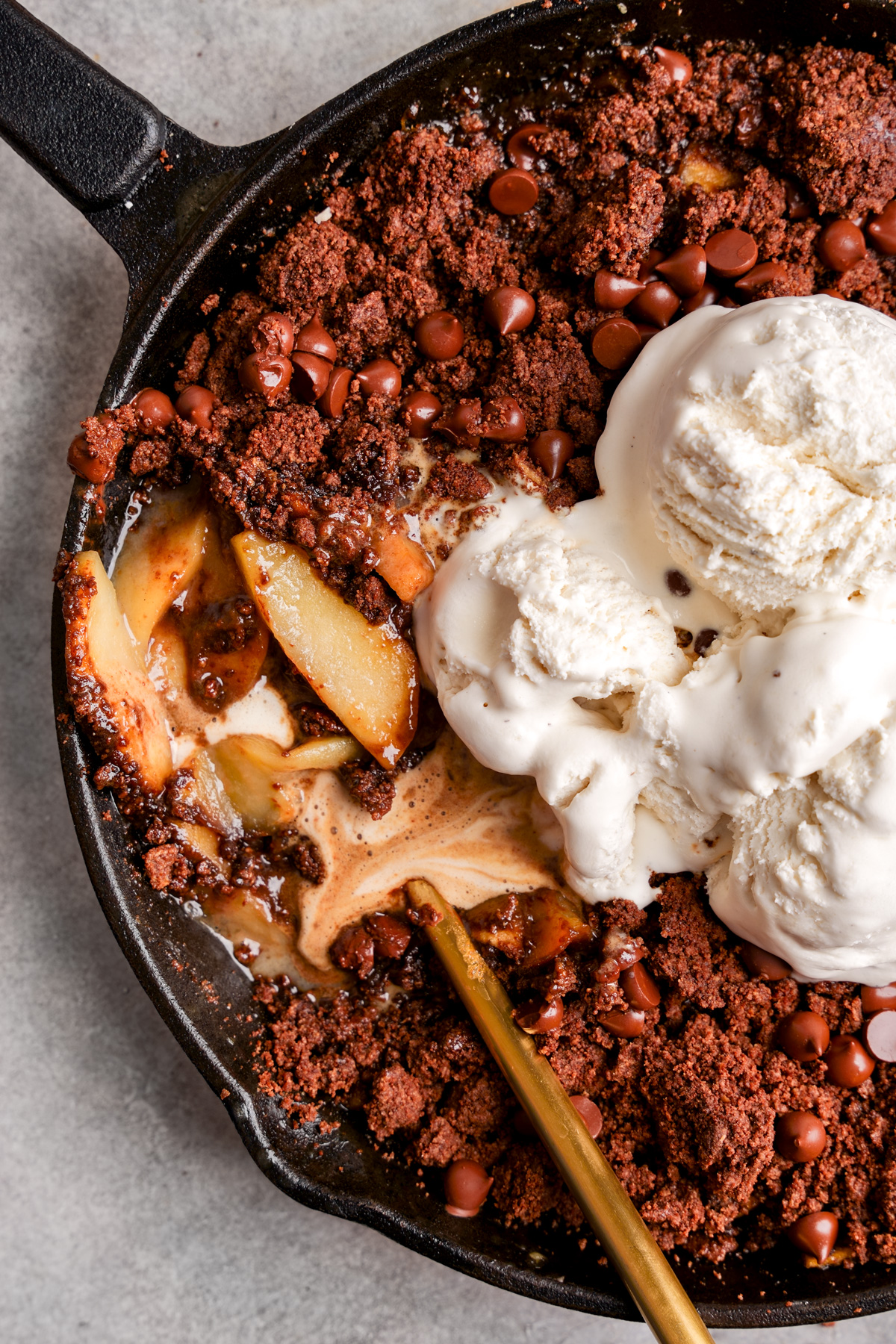 a close up of the chocolate vegan apple crisp with the melted chocolate and ice cream running through it