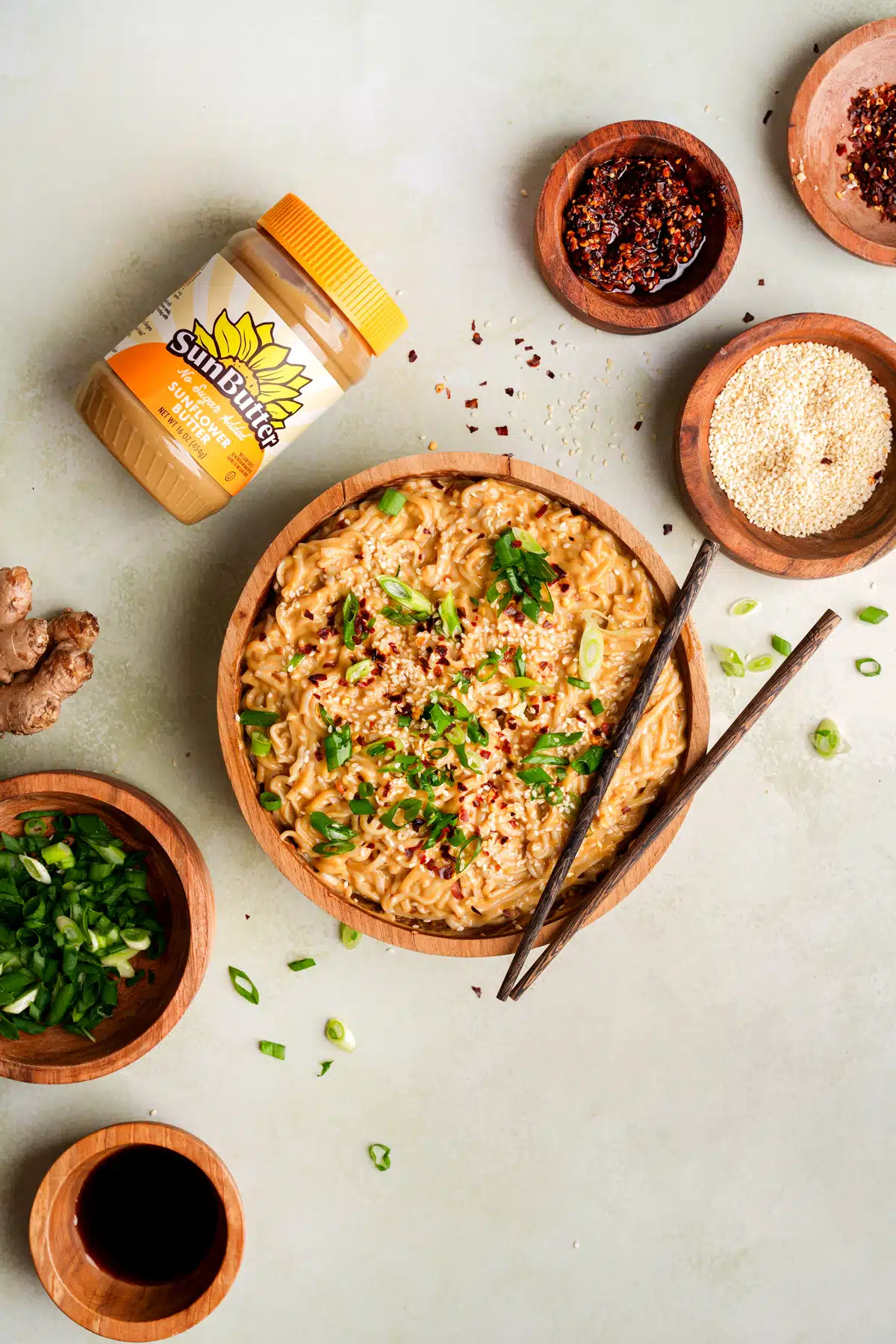 Looking down at the spicy sesame noodles with the sun butter container and small bowls filled with garnishes around the noodles.