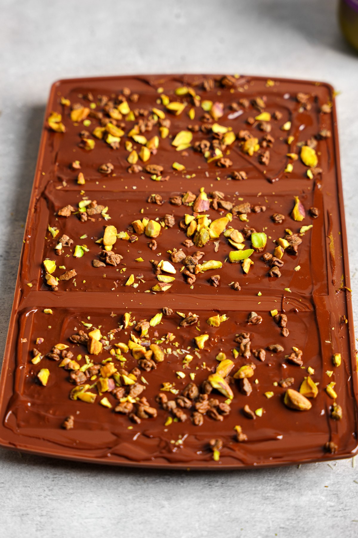 adding the pistachios and cacao nibs to the chocolate bars
