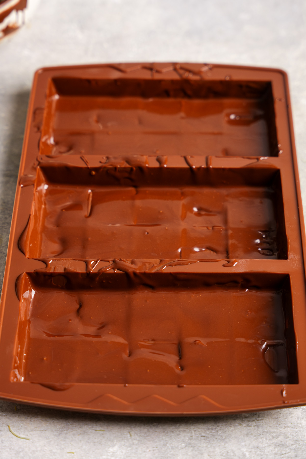 spreading melted chocolate onto the chocolate molds