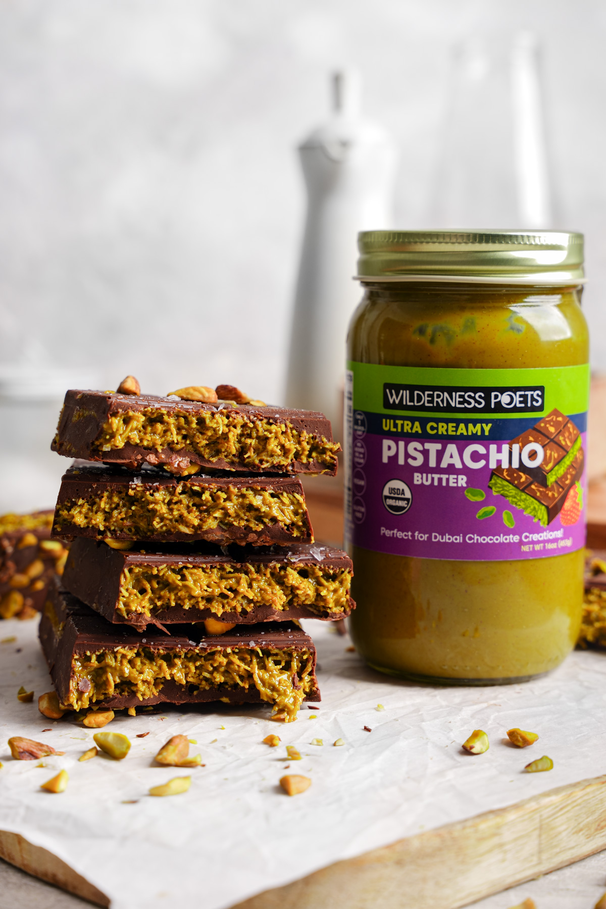 the dubai chocolate bar pieces stacked on top of each other to show the pistachio layer next to the ultra creamy pistachio butter